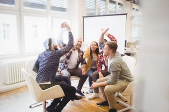 Excited creative business people giving high-five in meeting room at creative office